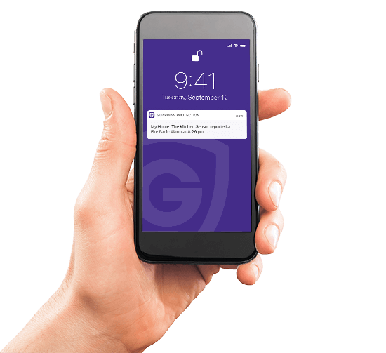 A hand holding a cell phone that is receiving a notification from the Guardian Protection app