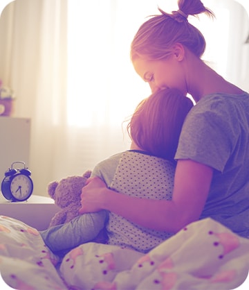 Female Guardian Protection customer hugging a child while sitting on a bed